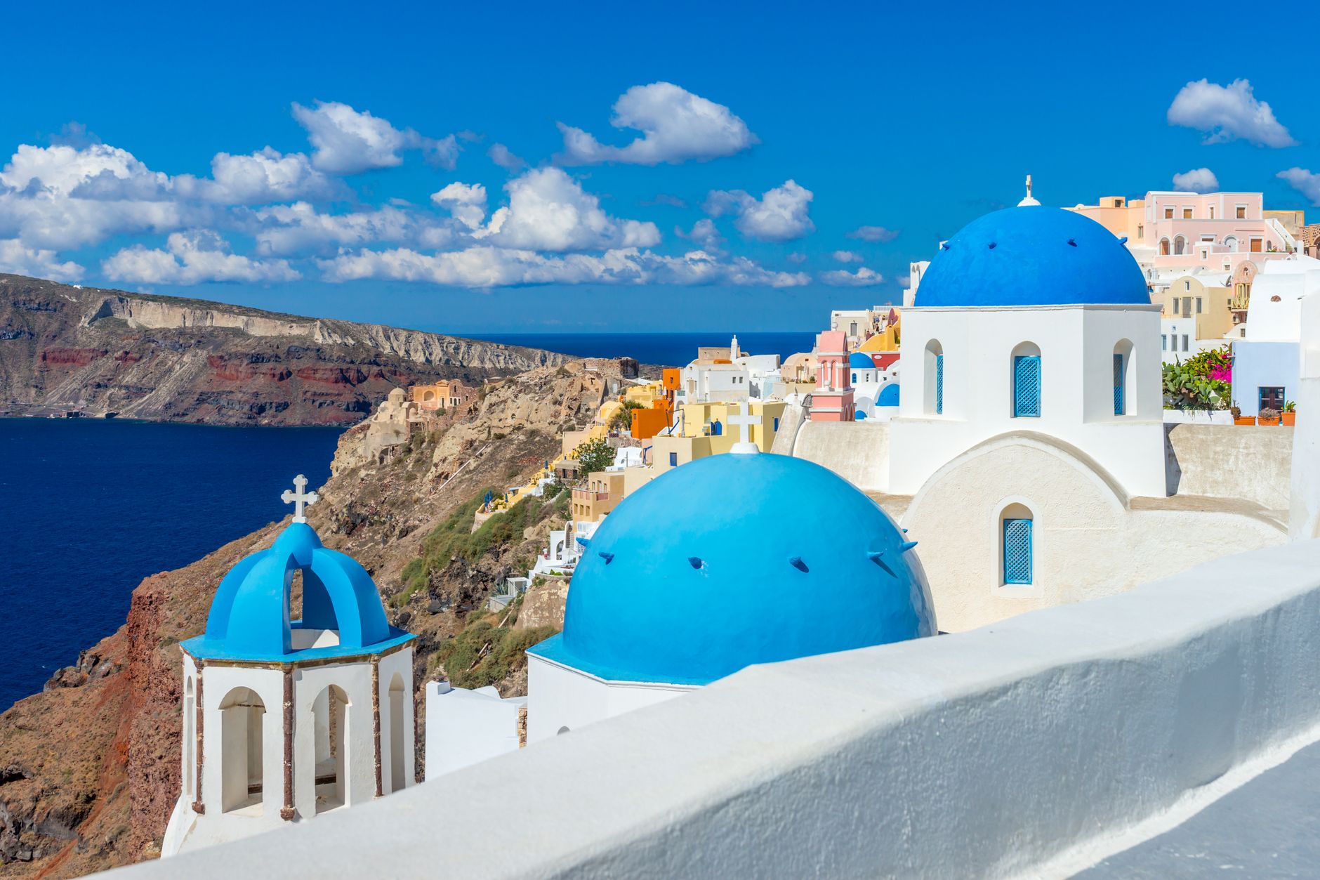 Capture the breathtaking scenery of Santorini's unique architecture and vibrant blue domes under a clear summe