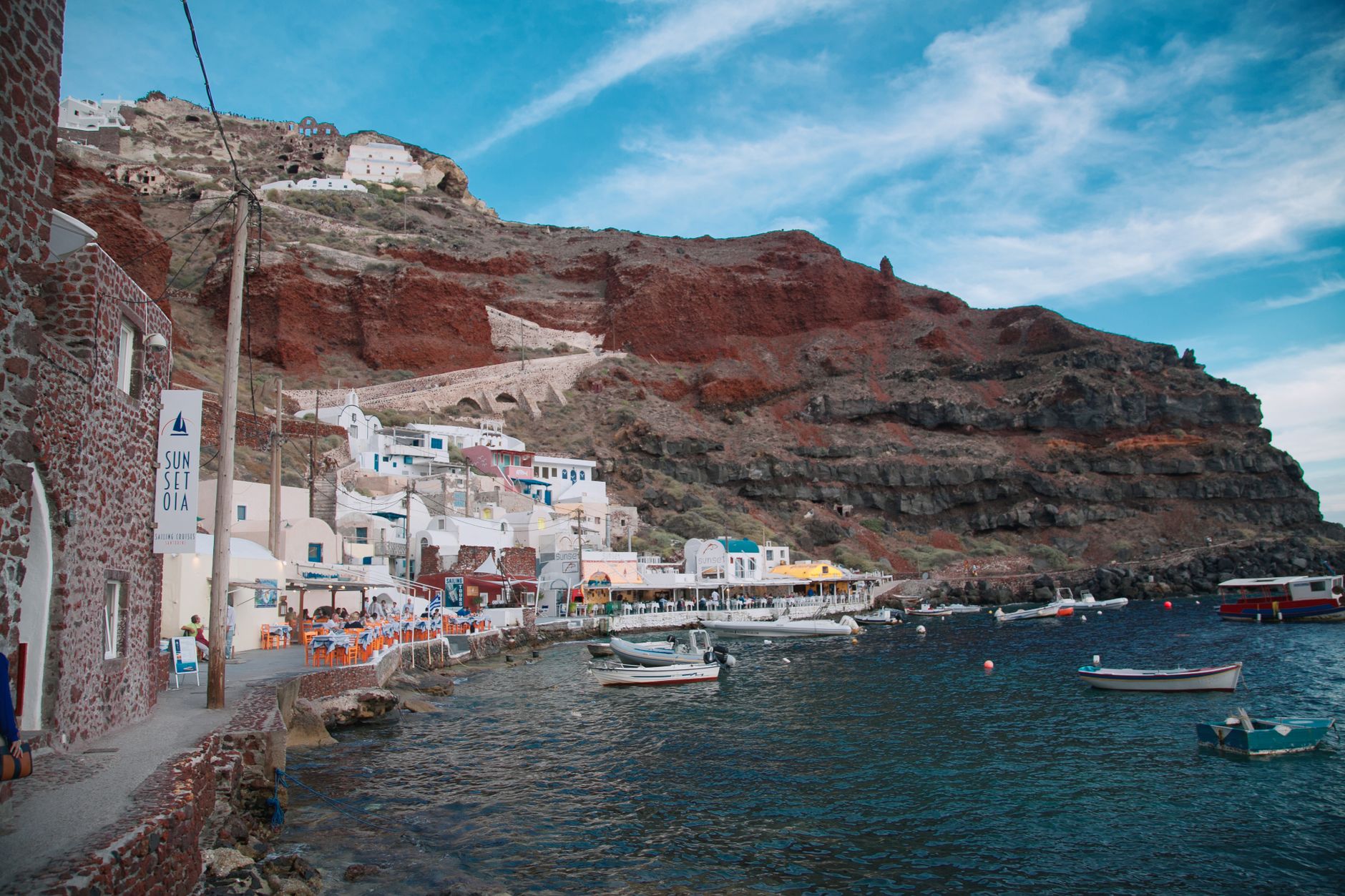 Scenic view of boats and seaside architecture in Oia, Santorini, Greece.
