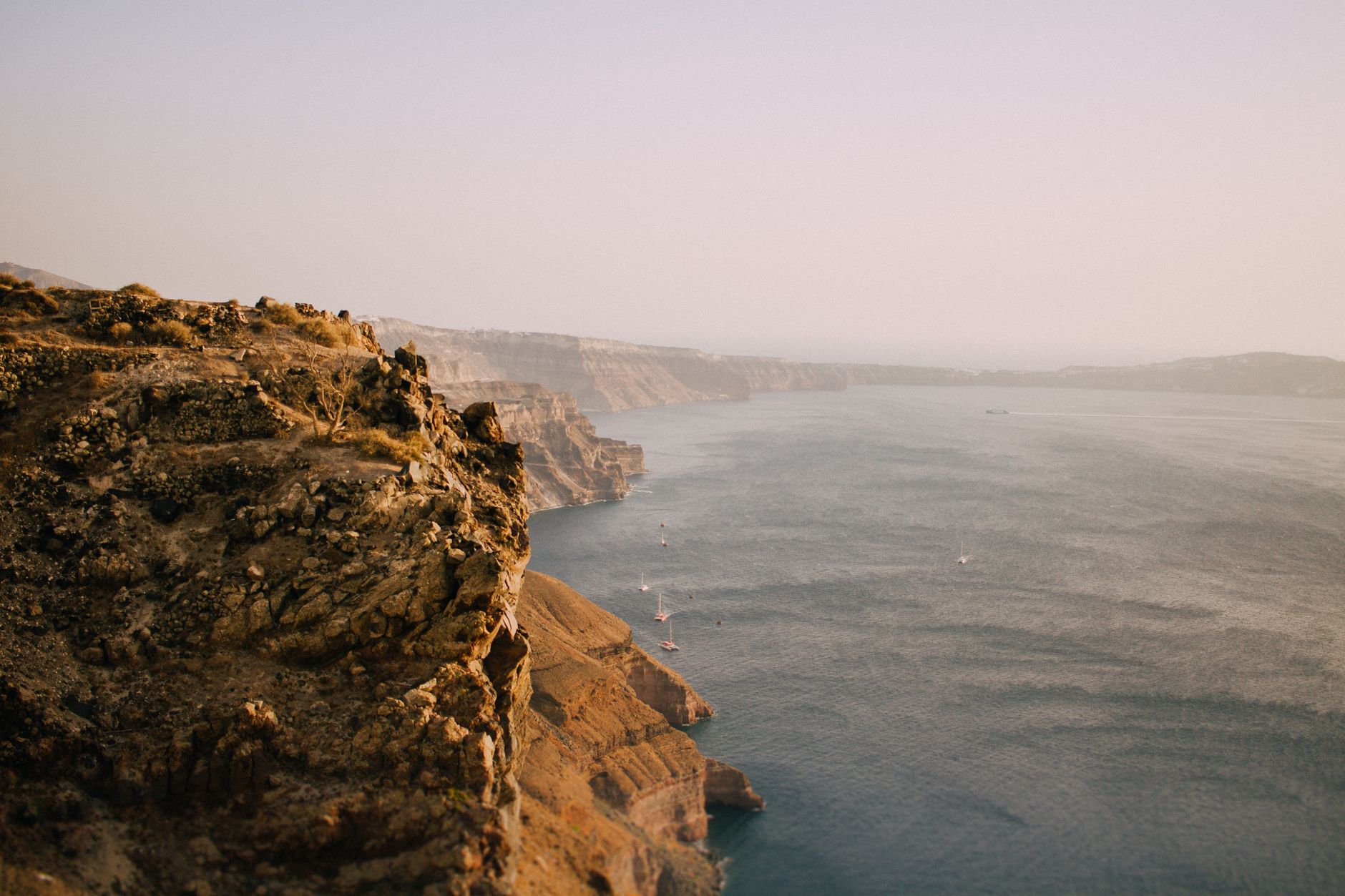 Breathtaking view of Santorini cliffs overlooking tranquil sea at dawn.
